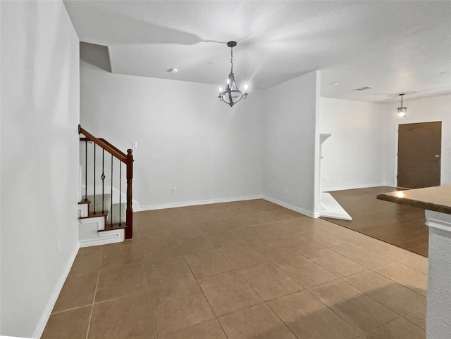 tiled spare room with an inviting chandelier