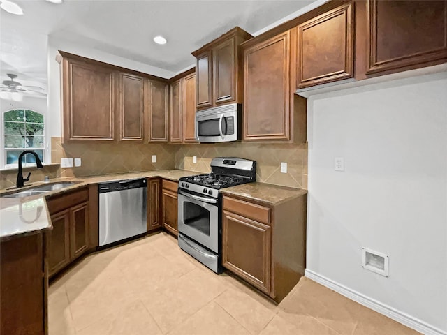 kitchen featuring appliances with stainless steel finishes, sink, ceiling fan, decorative backsplash, and light tile patterned floors