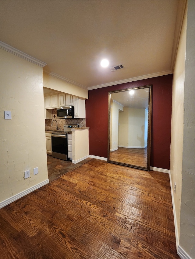 kitchen with backsplash, dark wood-type flooring, sink, ornamental molding, and stainless steel appliances