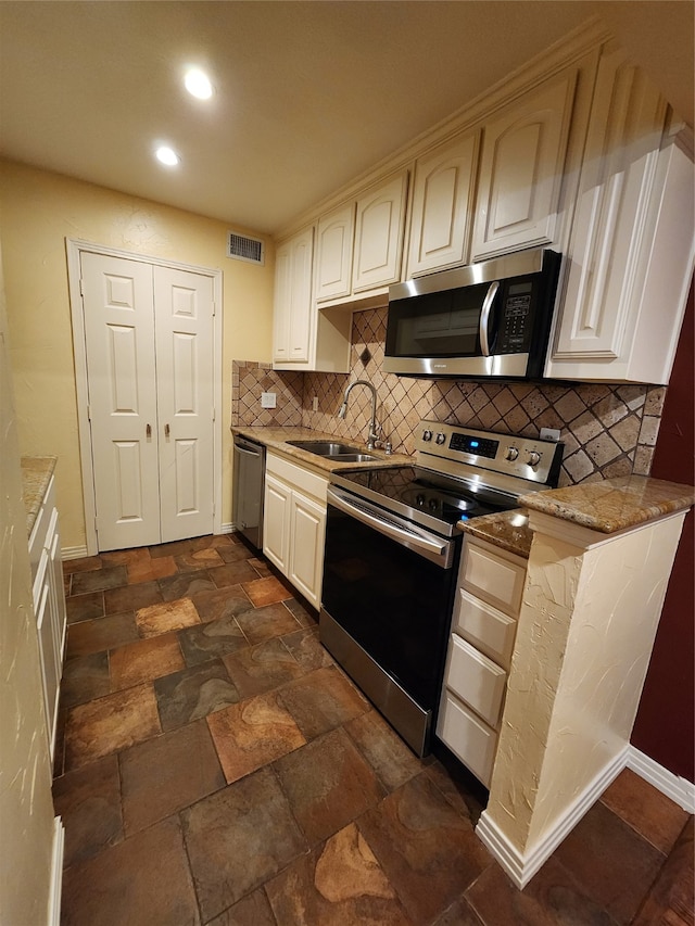 kitchen with backsplash, stainless steel appliances, light stone counters, and sink