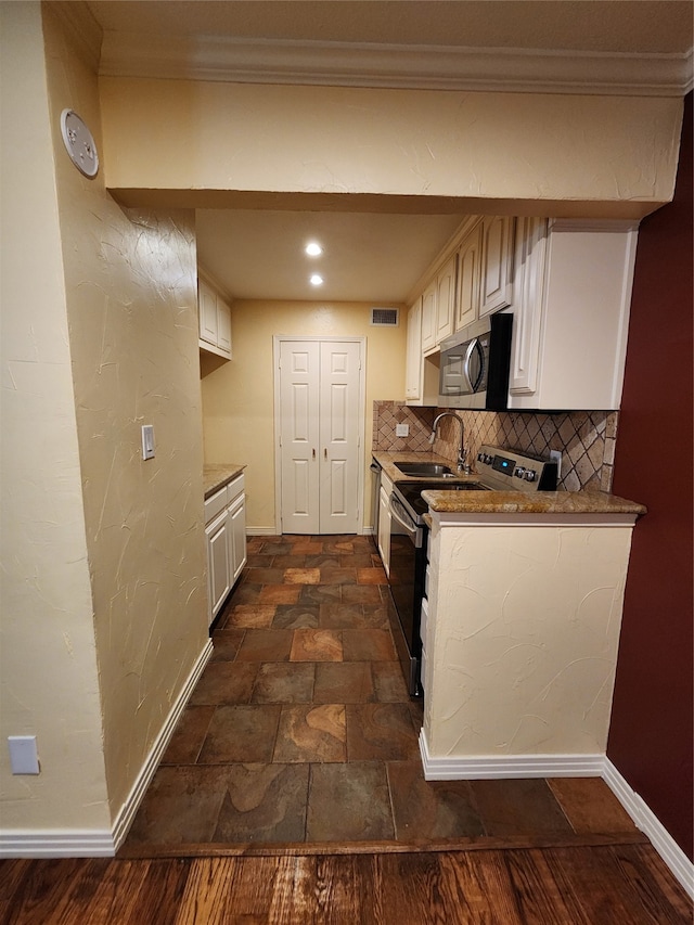 kitchen with decorative backsplash, stainless steel appliances, crown molding, sink, and white cabinetry