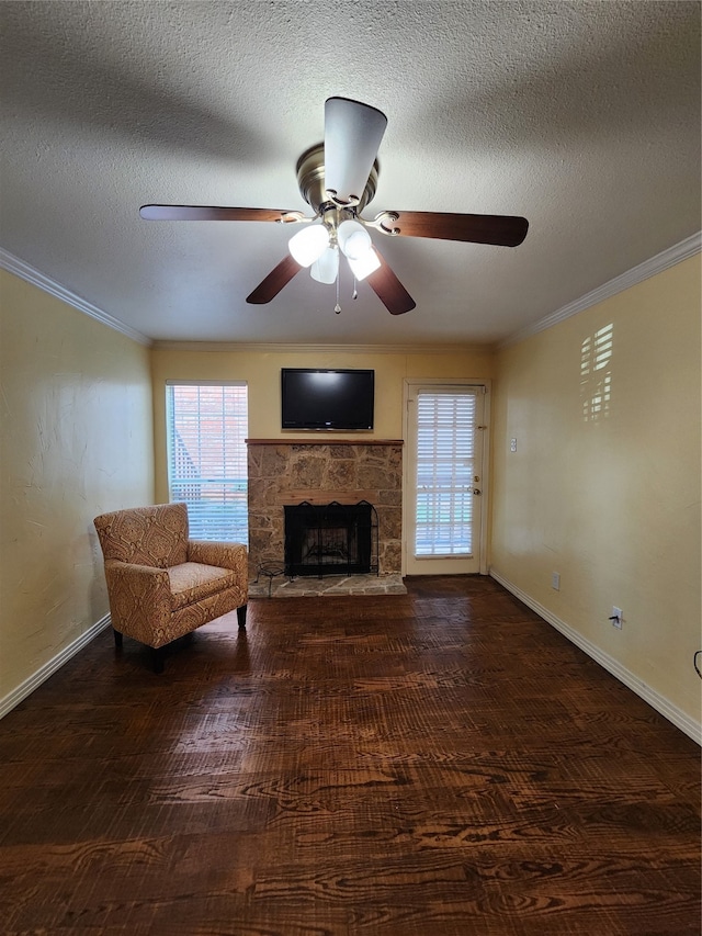 unfurnished living room featuring ceiling fan, dark wood-type flooring, a textured ceiling, a fireplace, and ornamental molding