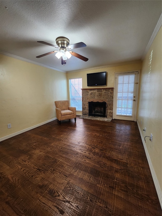 unfurnished living room featuring a textured ceiling, ceiling fan, dark wood-type flooring, crown molding, and a fireplace