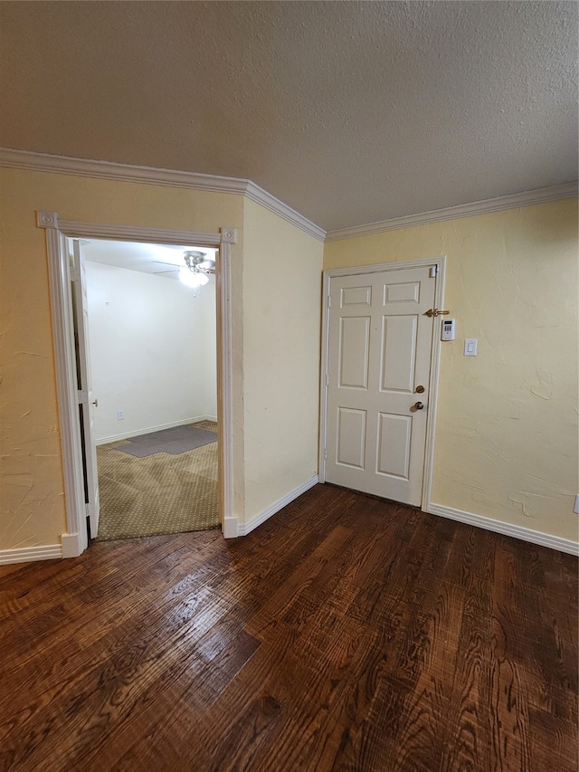 empty room featuring dark hardwood / wood-style floors, crown molding, and a textured ceiling