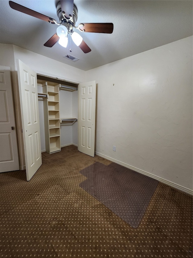 unfurnished bedroom with ceiling fan, a closet, and dark carpet