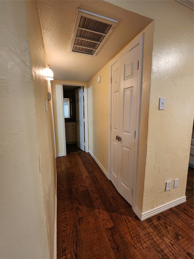 corridor with dark wood-type flooring and a textured ceiling