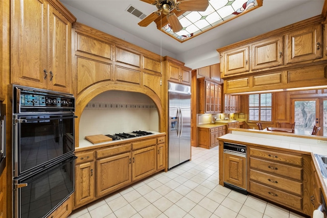 kitchen with built in refrigerator, double oven, ceiling fan, gas cooktop, and light tile patterned floors