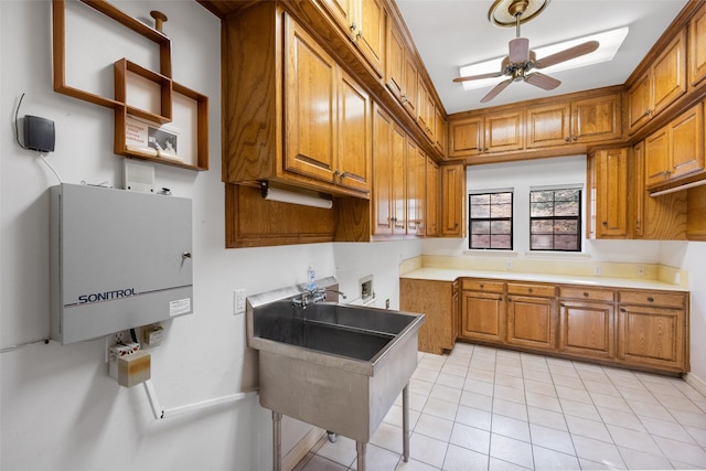 kitchen with ceiling fan, sink, water heater, and light tile patterned flooring