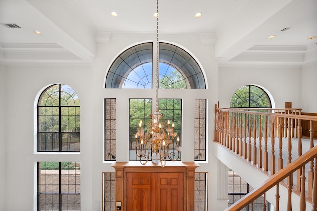 entryway featuring beam ceiling, a notable chandelier, a high ceiling, and ornamental molding