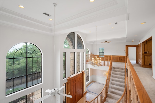 interior space with tile patterned floors, crown molding, ceiling fan with notable chandelier, and a tray ceiling