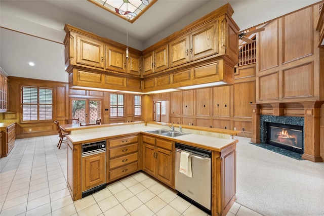 kitchen featuring kitchen peninsula, dishwasher, sink, and wood walls