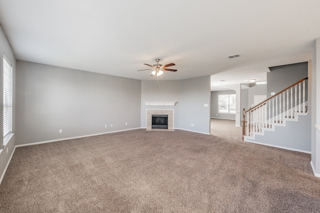 unfurnished living room featuring ceiling fan, carpet flooring, and a fireplace