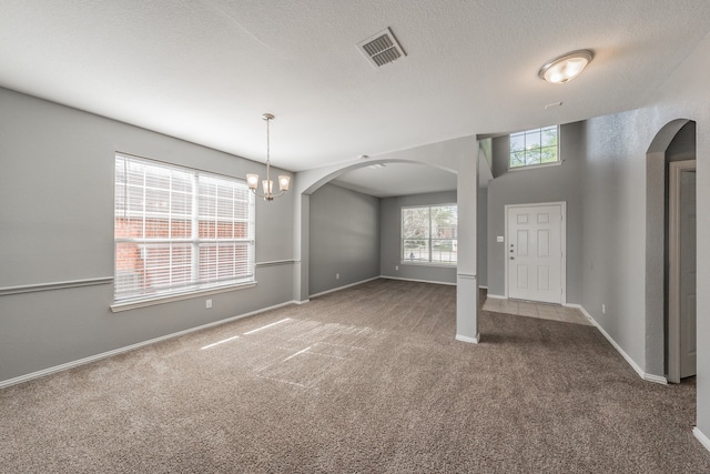 carpeted entryway featuring a textured ceiling and a chandelier