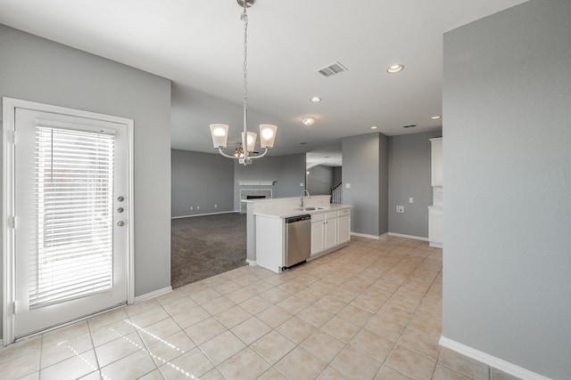 kitchen featuring light tile patterned flooring, a tile fireplace, hanging light fixtures, white cabinetry, and stainless steel dishwasher