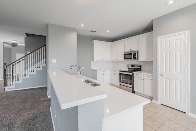 kitchen with tasteful backsplash, sink, white cabinetry, stainless steel appliances, and light colored carpet