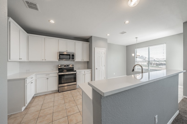 kitchen with white cabinetry, stainless steel appliances, light tile patterned floors, and backsplash