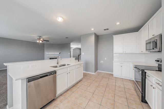 kitchen featuring backsplash, a center island with sink, sink, white cabinets, and appliances with stainless steel finishes