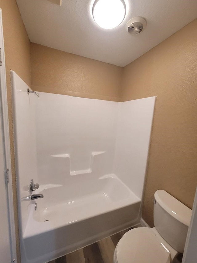 bathroom featuring toilet, shower / washtub combination, and hardwood / wood-style flooring