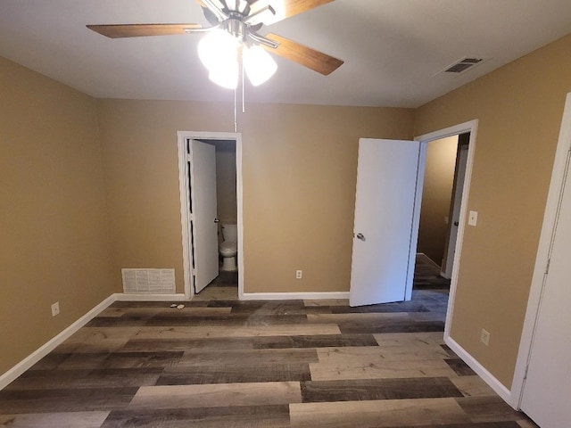 unfurnished bedroom with ensuite bath, dark wood-type flooring, and ceiling fan