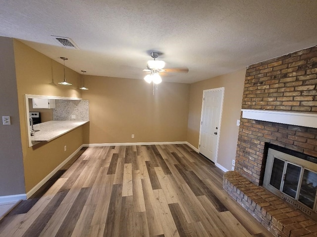 unfurnished living room with a textured ceiling, wood-type flooring, and ceiling fan