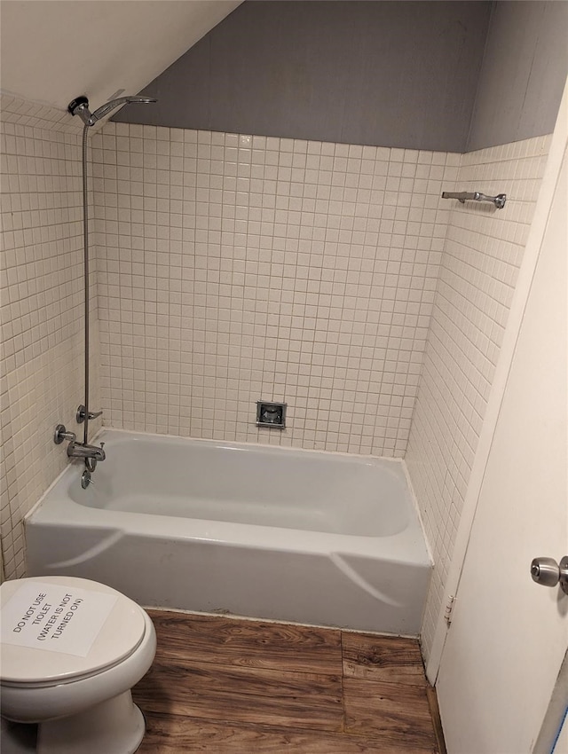 bathroom with toilet, wood-type flooring, and tiled shower / bath