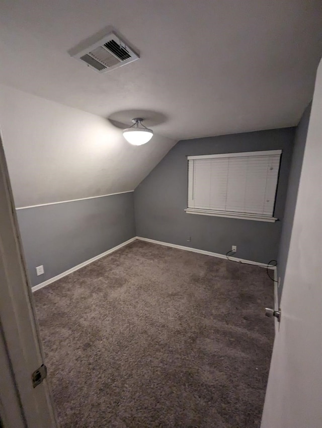 bonus room with lofted ceiling and dark carpet