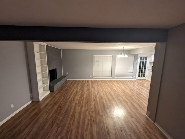 unfurnished living room with a chandelier, a fireplace, and hardwood / wood-style floors