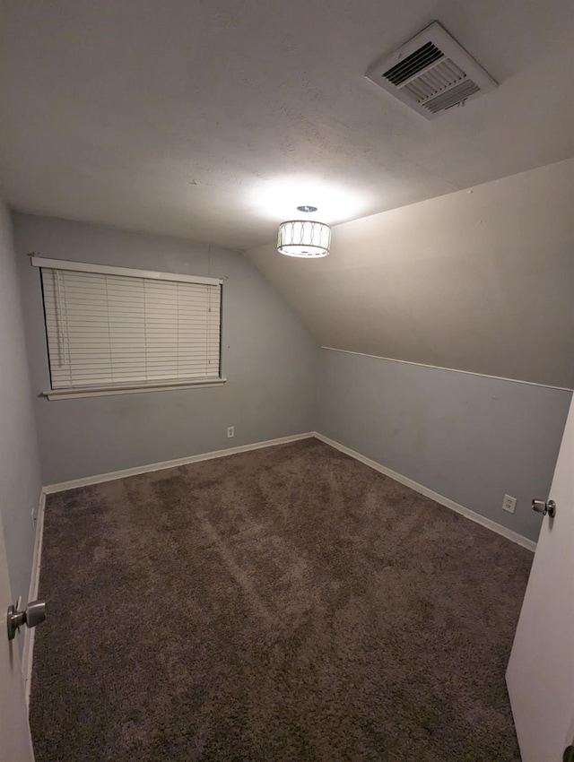 bonus room with dark colored carpet and vaulted ceiling