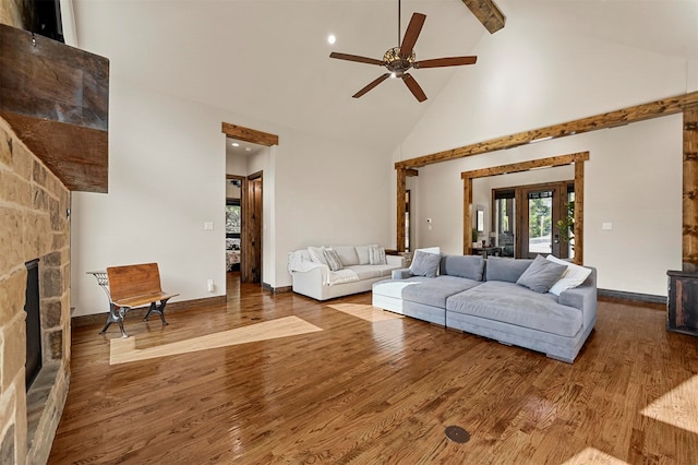 living room with hardwood / wood-style floors, ceiling fan, high vaulted ceiling, beamed ceiling, and a fireplace