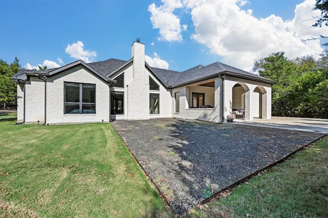 rear view of house featuring a patio and a lawn