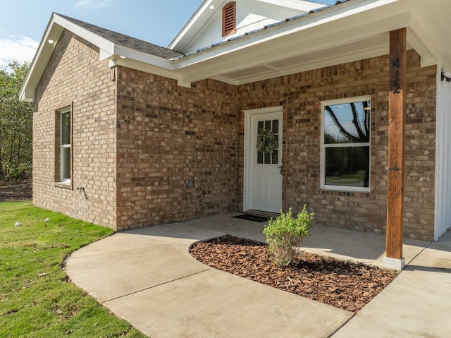 view of exterior entry with a patio and brick siding