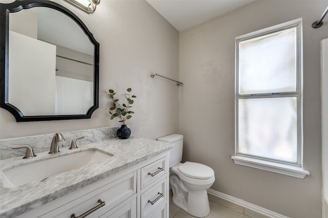 bathroom with a wealth of natural light, vanity, toilet, and tile patterned flooring