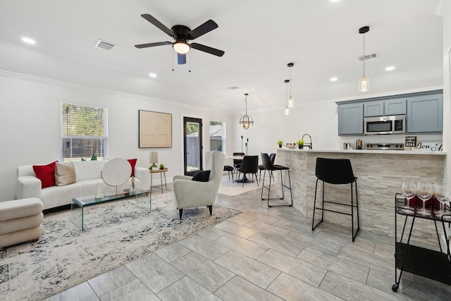 living room with crown molding, plenty of natural light, and ceiling fan with notable chandelier