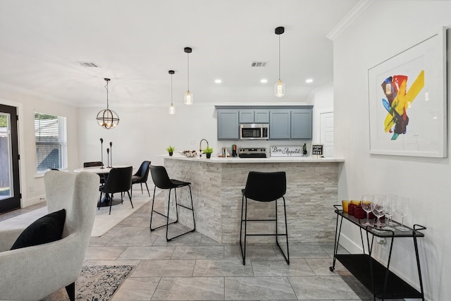 kitchen with stainless steel appliances, crown molding, hanging light fixtures, and a breakfast bar area