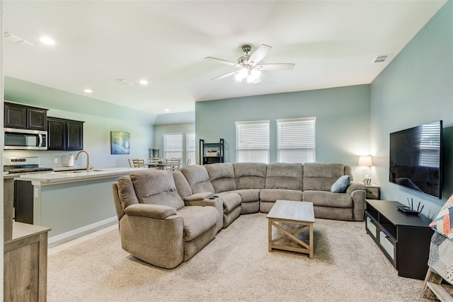 living room featuring light carpet, sink, and ceiling fan