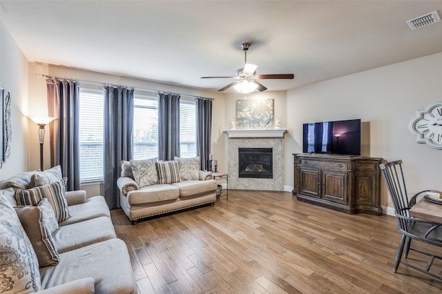 living room featuring a fireplace, light wood-type flooring, and ceiling fan