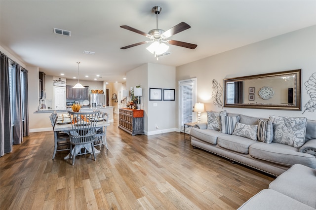 living room featuring ceiling fan, light hardwood / wood-style flooring, and a wealth of natural light