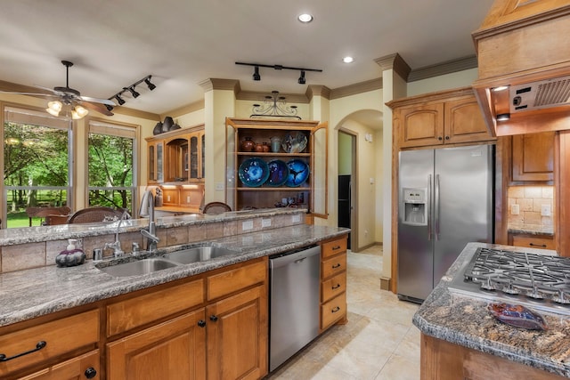 kitchen featuring appliances with stainless steel finishes, ornamental molding, sink, and dark stone counters