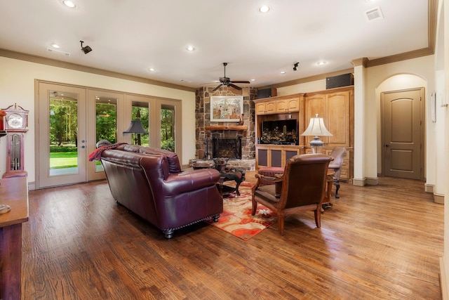 living room with light hardwood / wood-style floors, a stone fireplace, and crown molding