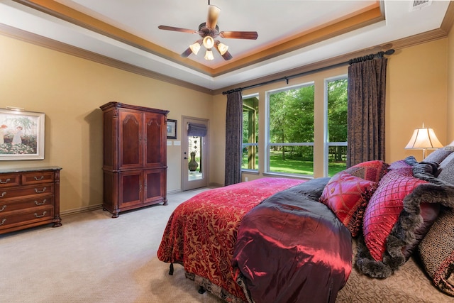 carpeted bedroom with ceiling fan, crown molding, a tray ceiling, and access to exterior