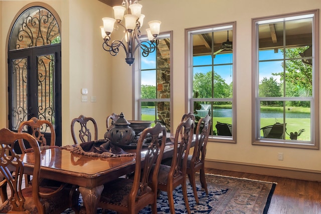 dining room featuring a notable chandelier, dark hardwood / wood-style floors, french doors, and a water view