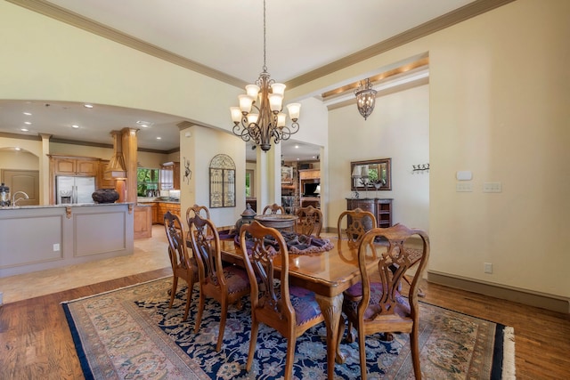 dining room with sink, crown molding, light hardwood / wood-style flooring, and an inviting chandelier