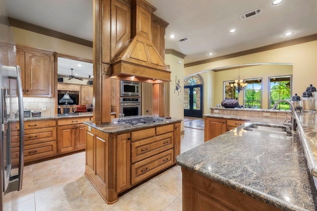 kitchen featuring a spacious island, backsplash, sink, appliances with stainless steel finishes, and ceiling fan with notable chandelier