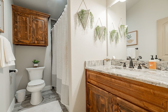 bathroom with toilet, vanity, and wood-type flooring