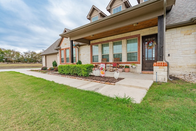 doorway to property featuring a porch, a garage, and a lawn