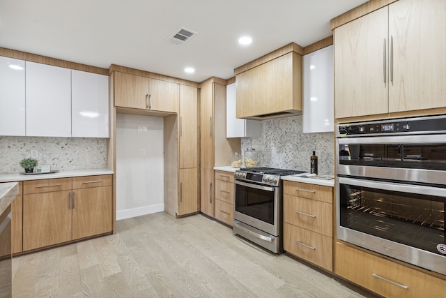 kitchen with white cabinetry, backsplash, stainless steel appliances, and light wood-type flooring