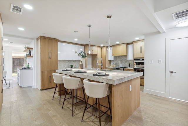 kitchen with light hardwood / wood-style floors, sink, pendant lighting, and white cabinets