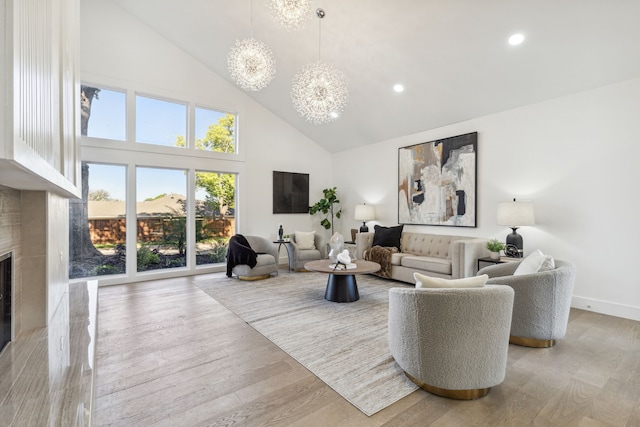 living room featuring light hardwood / wood-style floors, a chandelier, and high vaulted ceiling