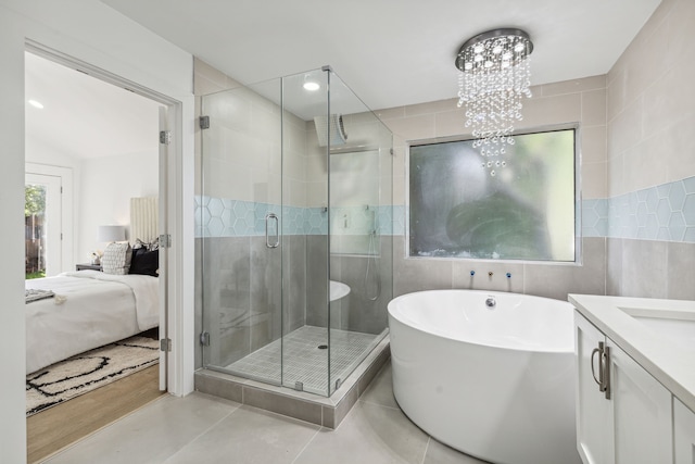 bathroom featuring tile patterned floors, independent shower and bath, vanity, tile walls, and a chandelier