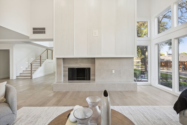 living room featuring a high ceiling, a tiled fireplace, and light hardwood / wood-style floors